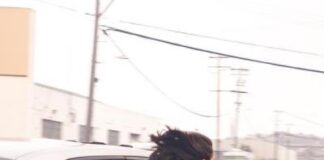 Woman seen leaning out of moving car holding AK-47