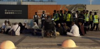 Travelers with luggage wait outside a metro station near King Khalid International Airport after the Riyadh airport attack