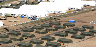 Aerial view of rows of green military tents and large white shelters at Wainwright, Alberta.