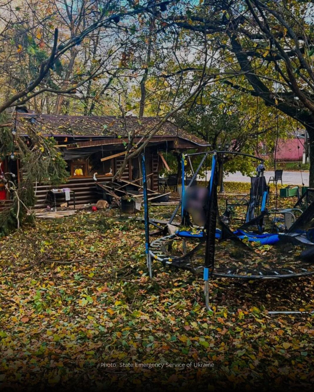 Damaged trampoline, fallen tree branches and a wrecked wooden pavilion in a leaf-covered park in Nova Vodolaha, Ukraine, after a drone strike
