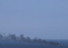 EU Lawmakers Urge Bloc to Weigh Naval Operation in Black Sea Merchant ship trailing a long plume of black smoke at sea under a hazy sky, illustrating calls for a Black Sea naval operation