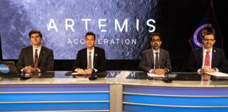 Four NASA officials seated at a news desk in front of an Artemis Acceleration screen showing the Moon's surface