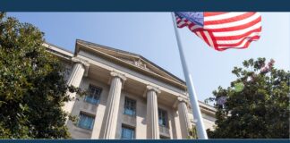 U.S. flag flying beside a columned federal building in a photo for the CIA contractor charged with leaking defense information