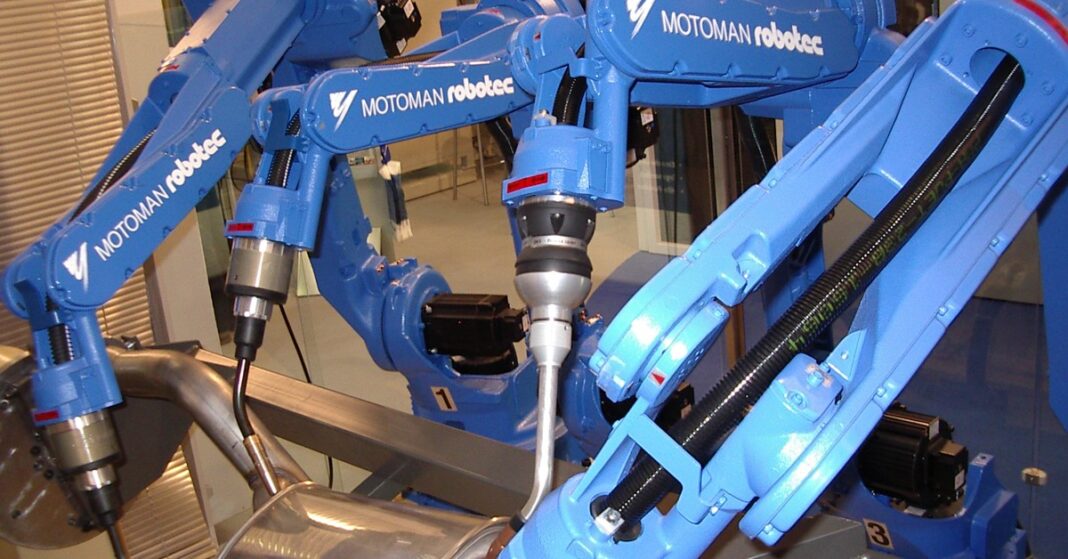 Blue Motoman industrial welding robots on a factory line, illustrating the Trump robotics tariffs story