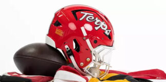 Maryland football helmet bearing the Terps script beside a football on red, white, black and gold fabric.