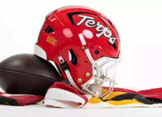 Maryland football helmet bearing the Terps script beside a football on red, white, black and gold fabric.