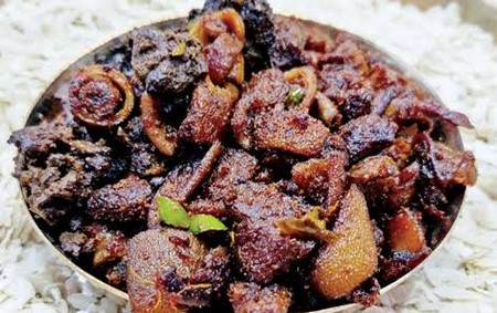 Browned goat offal with onion and chilies served in a dish over beaten rice