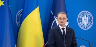 Romanian Prime Minister Luca Niculescu at a government podium in Bucharest, with European Union, Romanian and NATO flags behind him. (Romanian Government)