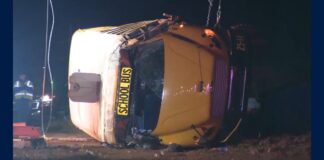 Salem High School bus crash scene showing a yellow school bus lying on its side at night.