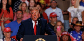 President Donald Trump speaks at a podium during a rally at Freeman Coliseum in San Antonio.