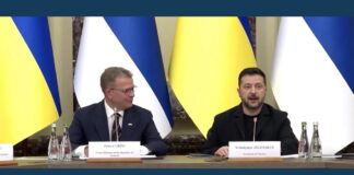 Petteri Orpo and Volodymyr Zelenskyy seated before Finnish and Ukrainian flags at a news conference on Ukraine-Finland cooperation.
