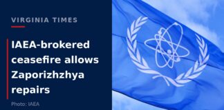 The flag of the International Atomic Energy Agency flying against a blue sky during the Zaporizhzhya nuclear plant ceasefire in Ukraine.
